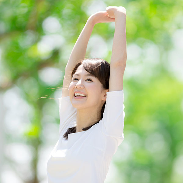 腕を上げてストレッチしながら微笑む女性