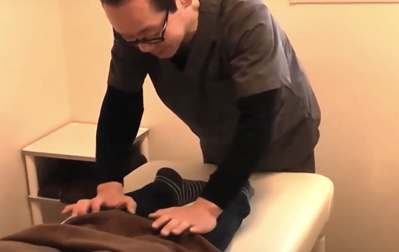 ふくらはぎを押して検査する院長