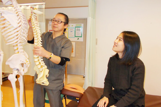 背骨の模型を使ってお客様に説明している院長とお客様