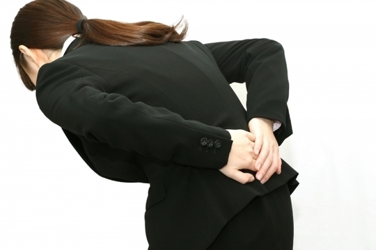 腰を押さえている女性の後ろ姿